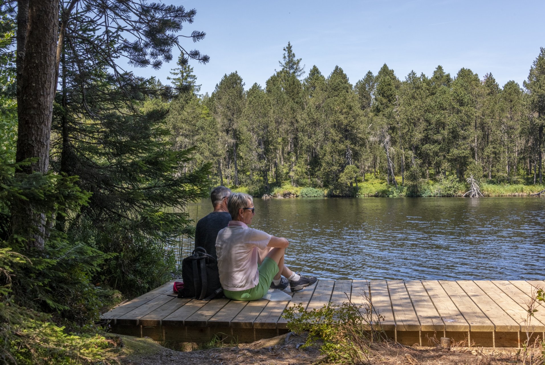 Des touristes profitent du calme au bord de l'étang de la Gruère.