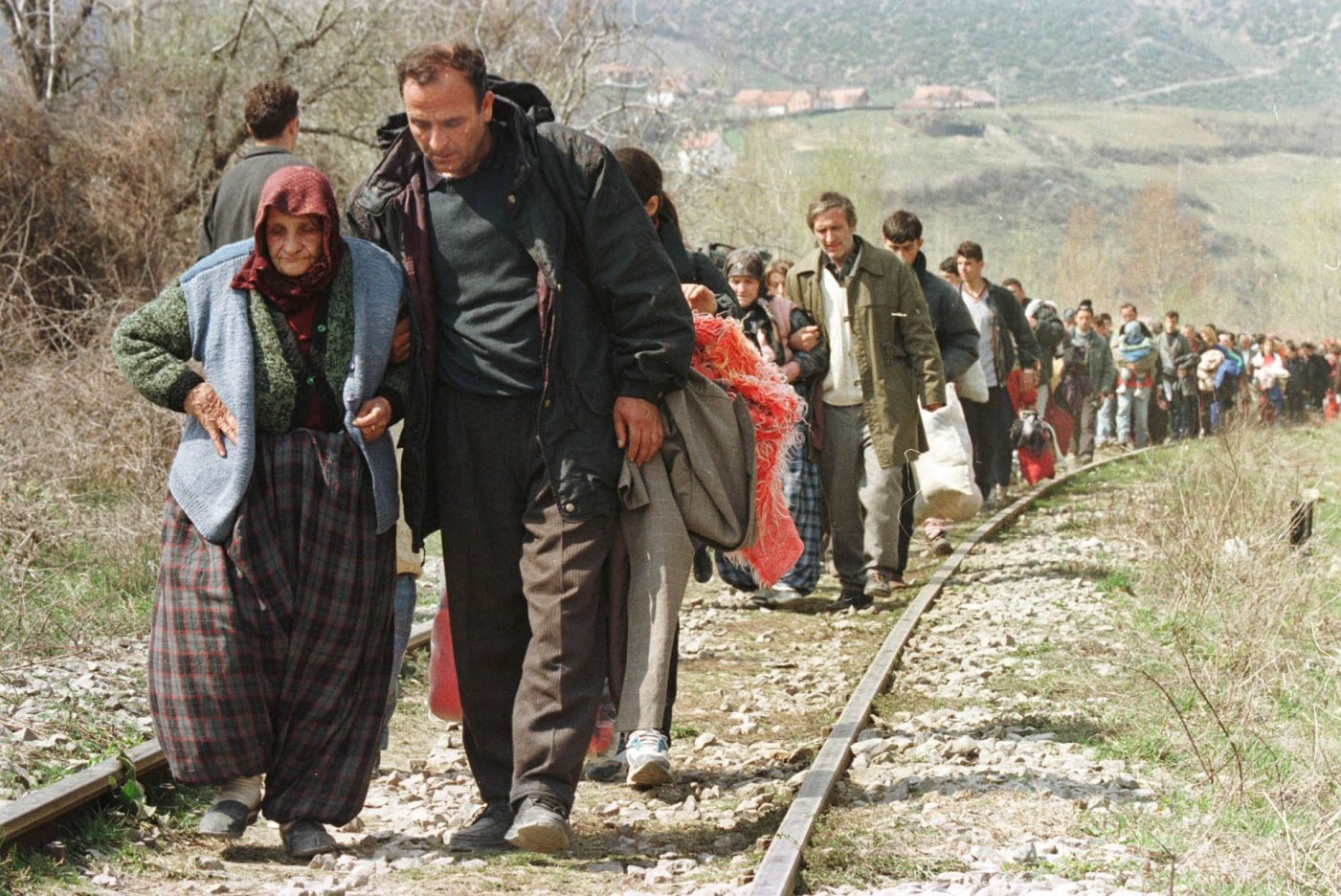 A man helps his mother as a convoy of thousands of refugees arrived in Blace, Macedonia, on the border crossing with Kosovo Thursday April 1, 1999. As NATO airstrikes continue ten of thousands Kosovars are forced to flee to neighbouring Macedonia. (KEYSTONE/AP Photo/Peter Dejong)