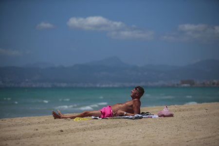 A German tourist takes a sunbath at the beach of Palma de Mallorca, Spain, Monday, June 15, 2020. Borders opened up across Europe on Monday after three months of coronavirus closures that began chaotically in March. But many restrictions persist, it's unclear how keen Europeans will be to travel this summer and the continent is still closed to Americans, Asians and other international tourists. (AP Photo/Joan Mateu)